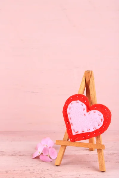 Hermoso corazón pequeño caballete decorativo sobre fondo rosa —  Fotos de Stock