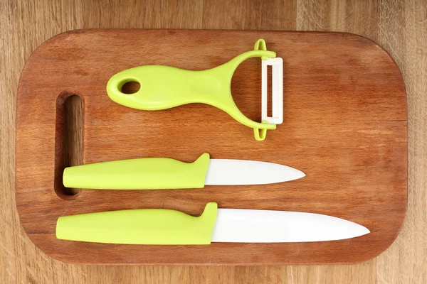 Cuchillos de cocina y tabla de cortar sobre mesa de madera —  Fotos de Stock
