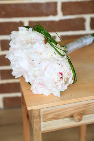 Beautiful wedding bouquet on   wooden stand on bricks background — Stock Photo, Image