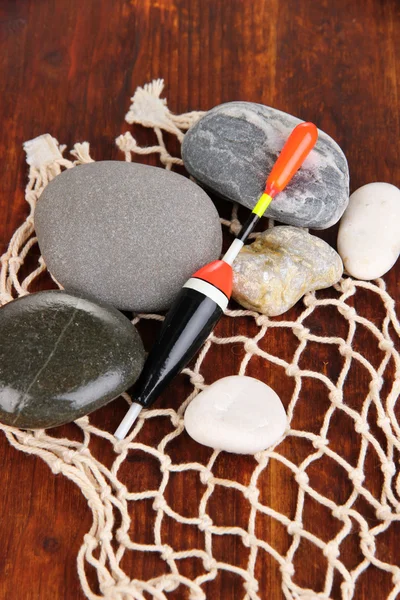 Rybářské plovák s kameny na dřevěný stůl detail — Stock fotografie