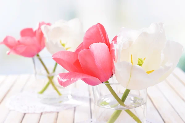 Hermosos tulipanes en cubo en jarrón sobre mesa sobre fondo claro —  Fotos de Stock