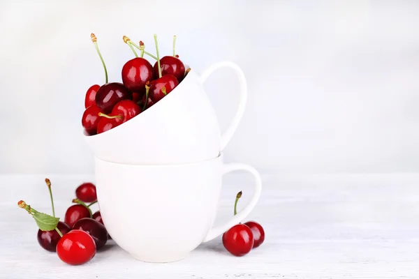 Ripe sweet cherries in cup on wooden table — Stock Photo, Image