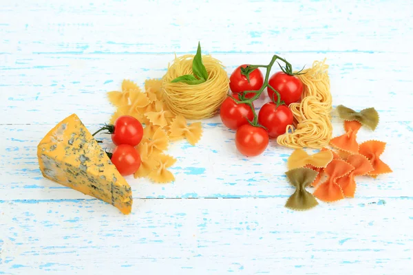 Verschiedene Nudeln, Käse und Tomaten auf Holztisch in Großaufnahme — Stockfoto