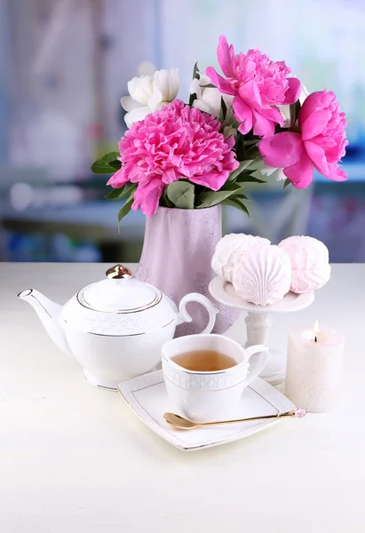 Composition of beautiful peonies in vase, tea in cup and marshmallow, on table, on light background Royalty Free Stock Images