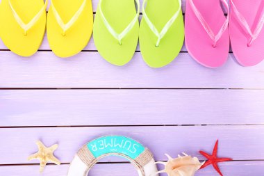 Renkli ahşap arka planda parlak parmak arası terlikler