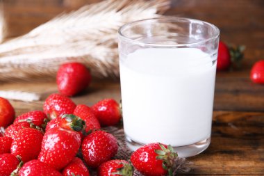 Olgun tatlı çilek ve süt rengi ahşap zemin ile cam