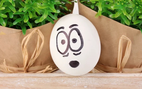 White egg with funny face near green bushes — Stock Photo, Image