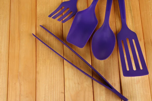 Plastic kitchen utensils on wooden background — Stock Photo, Image