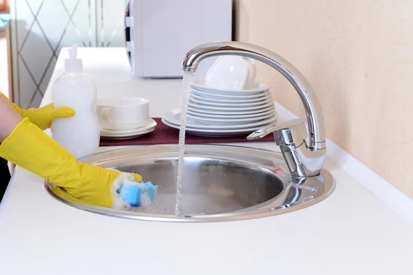Chiudi le mani della donna che lava i piatti in cucina — Foto Stock