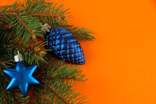 Beautiful Christmas decorations on fir tree on orange background — Stock Photo, Image
