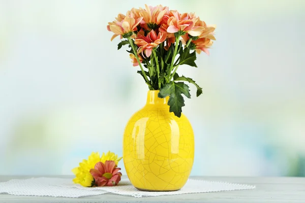 Bellissimi fiori in vasi, su tavolo di legno, su sfondo chiaro — Foto Stock