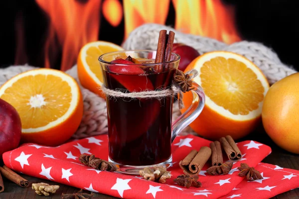 Fragrant mulled wine in glass on napkin on fire background — Stock Photo, Image