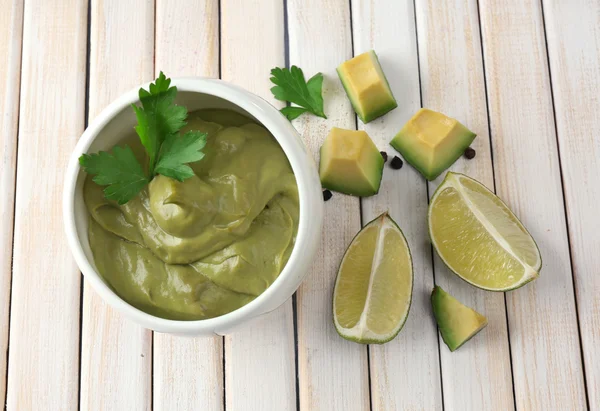 Fresh guacamole in bowl on wooden table — Stock Photo, Image