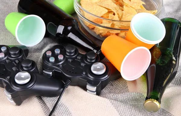 Svart spelenheter och skål med snacks på färg Pläd bakgrund — Stockfoto