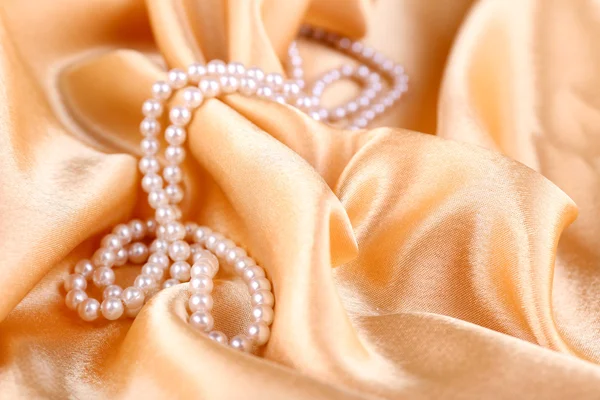 Beautiful pearls on golden silk cloth — Stock Photo, Image