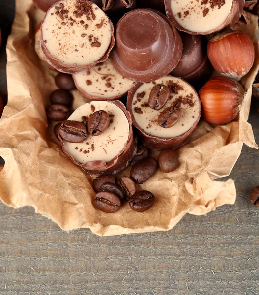 Tasty chocolate candies with coffee beans and nuts on wooden background — Stock Photo, Image