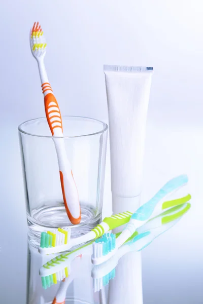 Toothbrushes in glass on light grey background — Stock Photo, Image