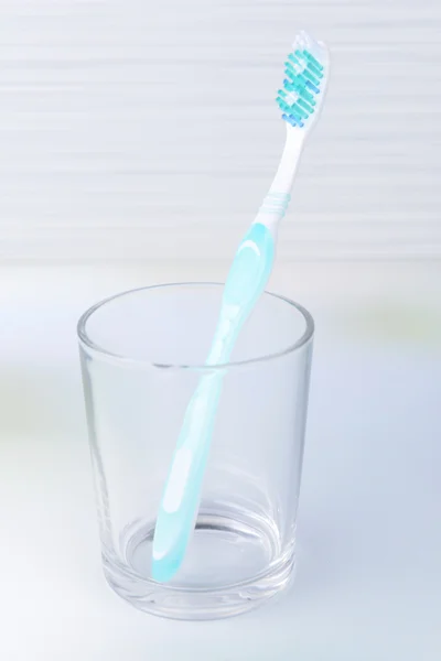 Toothbrush in glass on table on light background — Stock Photo, Image