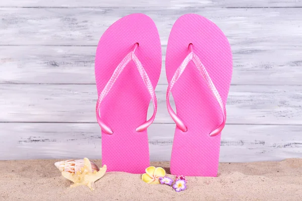 Bright flip-flops on sand, on wooden background — Stock Photo, Image