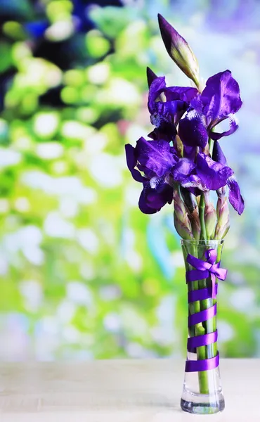 明るい背景上の木製のテーブルの上の花瓶に紫色のアイリスの花 — ストック写真