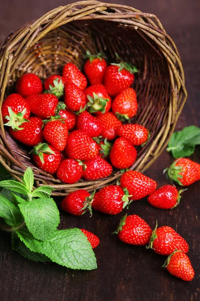 Mogna söta jordgubbar i rotting korg på trä bakgrund — Stockfoto