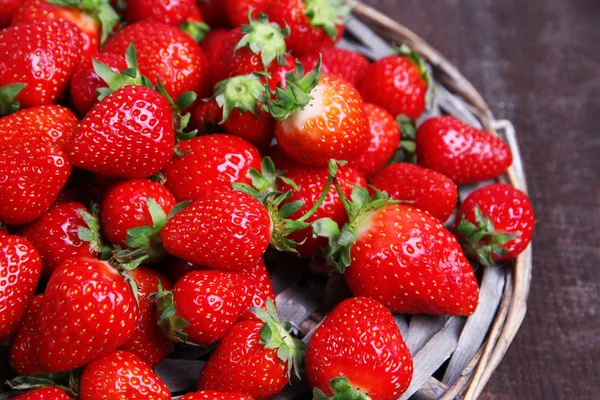 Ripe sweet strawberries on  wicker mat, on color wooden background — Stock Photo, Image