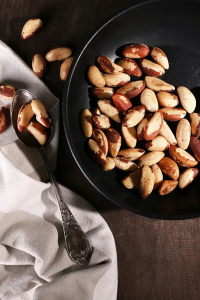 Tasty brasil nuts in pan on wooden background — Stock Photo, Image