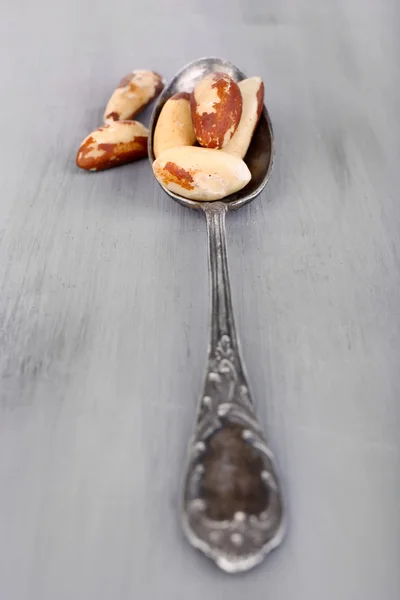 老式勺子与美味巴西坚果在木制的背景上 — 图库照片