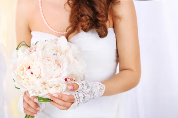 Невеста держит свадебный букет белых пионов, крупным планом, на светлом фоне — стоковое фото