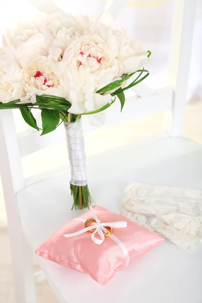 Hermoso ramo de boda y almohada decorativa para anillos de boda en la silla sobre fondo claro —  Fotos de Stock