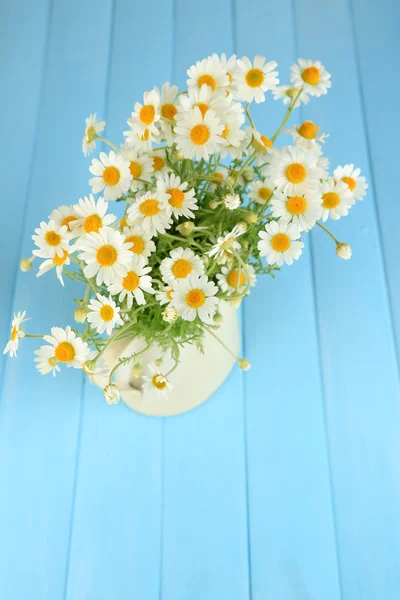 Chamomiles in jug  on color wooden background — Stock Photo, Image