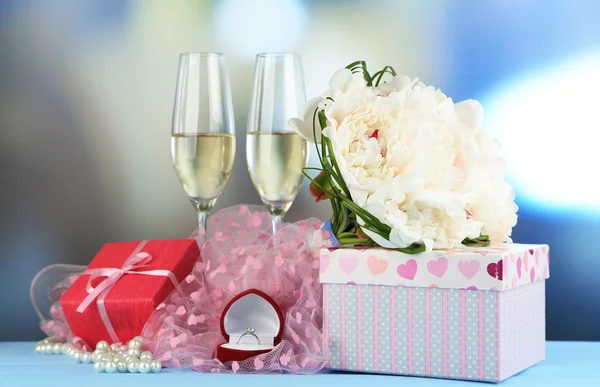 Hermoso ramo de bodas, caja de regalo y copas de vino sobre mesa de madera, sobre fondo brillante — Foto de Stock