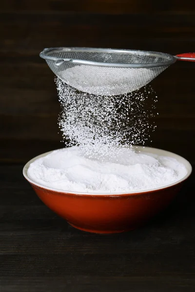 Mehl in Schüssel auf Tisch auf Holzgrund sieben — Stockfoto