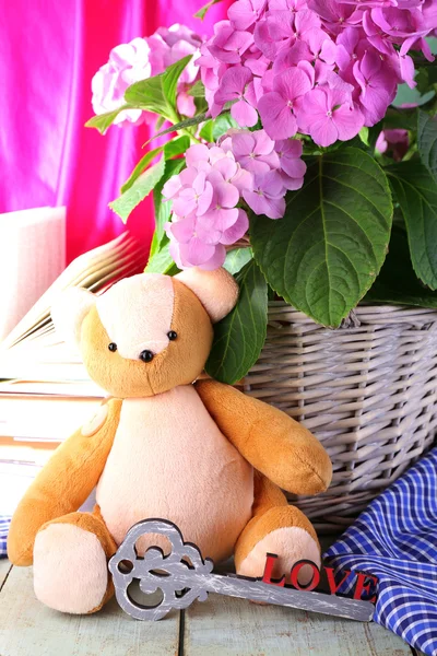 Hydrangea in basket with teddy bear and books close-up — Stock Photo, Image