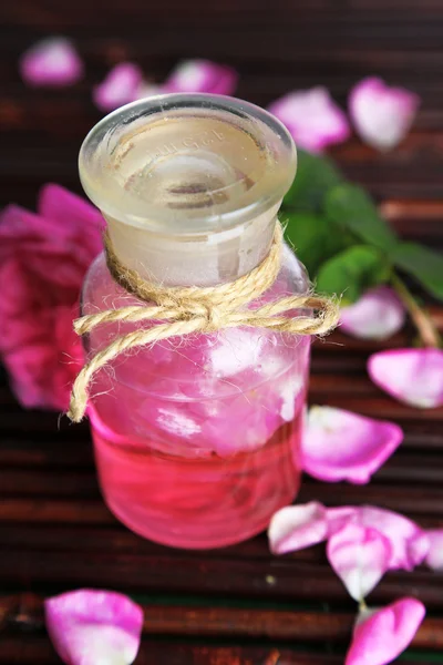 Rose oil in bottle on bamboo mat background — Stock Photo, Image