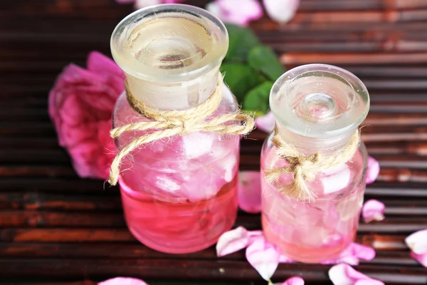 Aceite de rosa en botellas sobre fondo de estera de bambú — Foto de Stock
