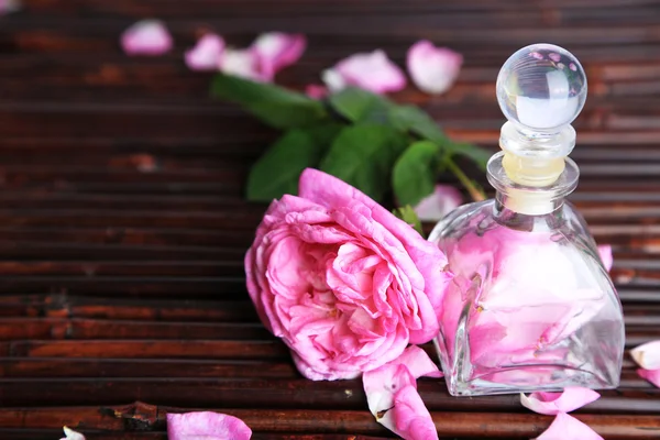 Rose oil in bottle on bamboo mat background — Stock Photo, Image