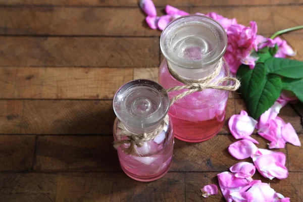 Olejek różany w butelkach na kolor drewniane tła — Zdjęcie stockowe