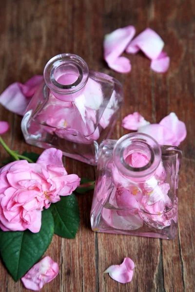 Óleo de rosa em garrafas sobre fundo de madeira cor — Fotografia de Stock
