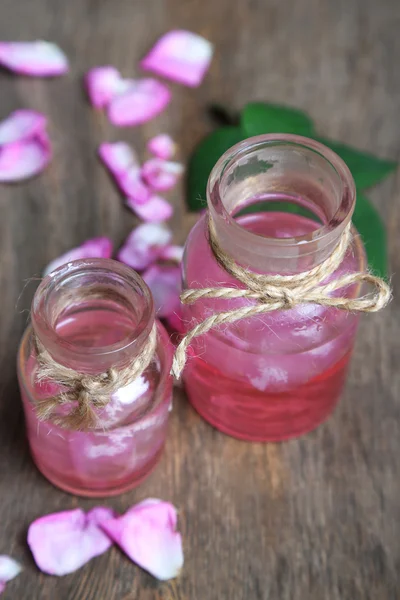 Aceite de rosa en botellas sobre fondo de madera de color —  Fotos de Stock