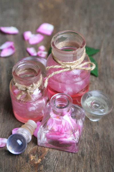 Olio di rosa in bottiglie su sfondo di legno di colore — Foto Stock