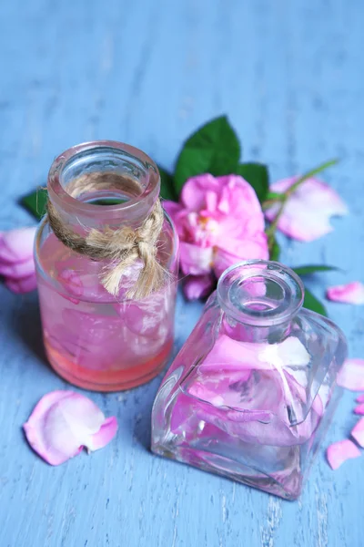 Розовое масло в бутылках на фоне цвета дерева — стоковое фото