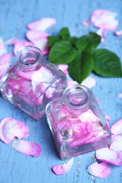 Rose olie i flasker på farve træ baggrund - Stock-foto