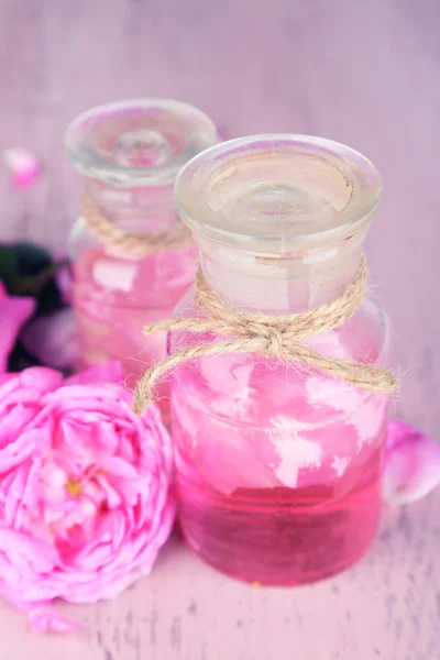 Rosenöl in der Flasche auf farbigem Holzhintergrund — Stockfoto