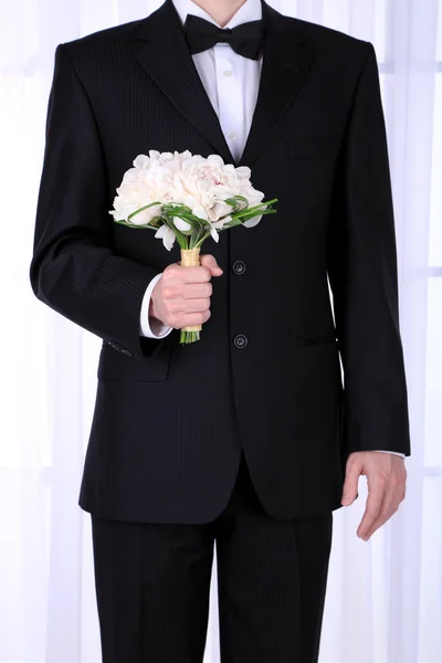 Мужчина держит свадебный букет на светлом фоне — стоковое фото