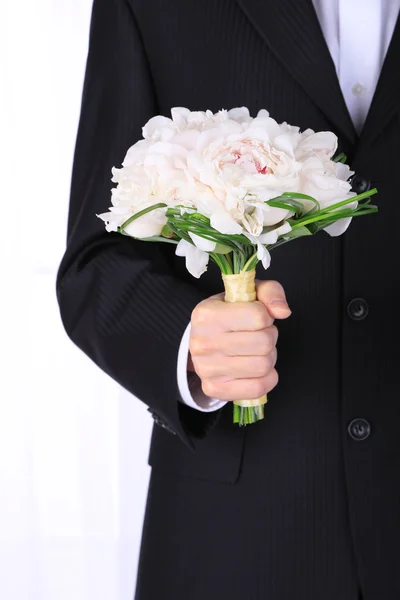 Mann hält Hochzeitsstrauß auf hellem Hintergrund — Stockfoto