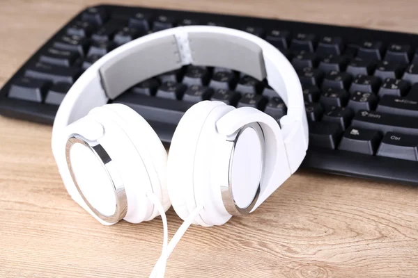 Headphone and keyboard close-up on wooden desk background — Stock Photo, Image