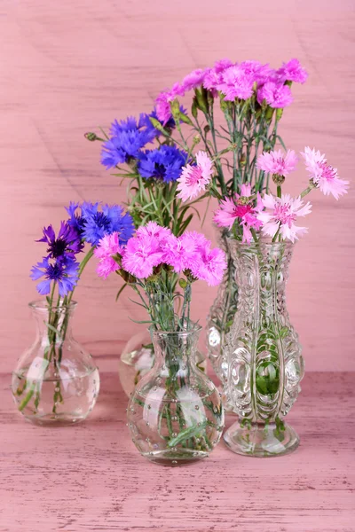 Beautiful summer flowers in vases on pink wooden background — Stock Photo, Image