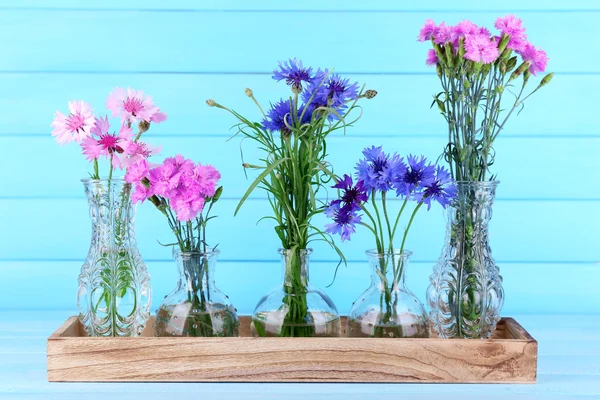 Beautiful summer flowers in vases on blue wooden background — Stock Photo, Image