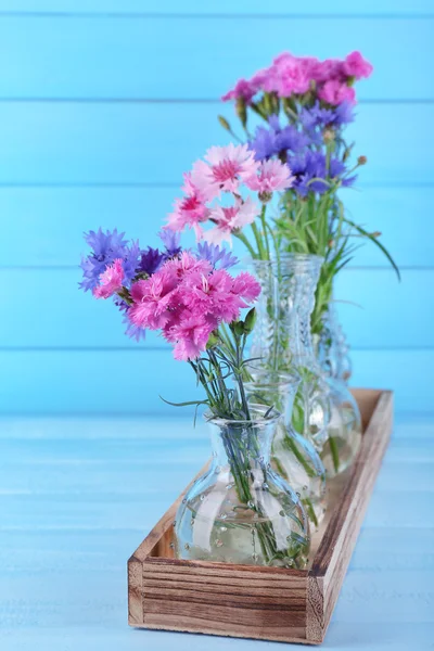 Schöne Sommerblumen in Vasen auf blauem Holzgrund — Stockfoto